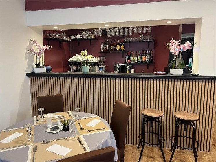 Le comptoir en bois et ses tabourets, orchidées sur le bar
