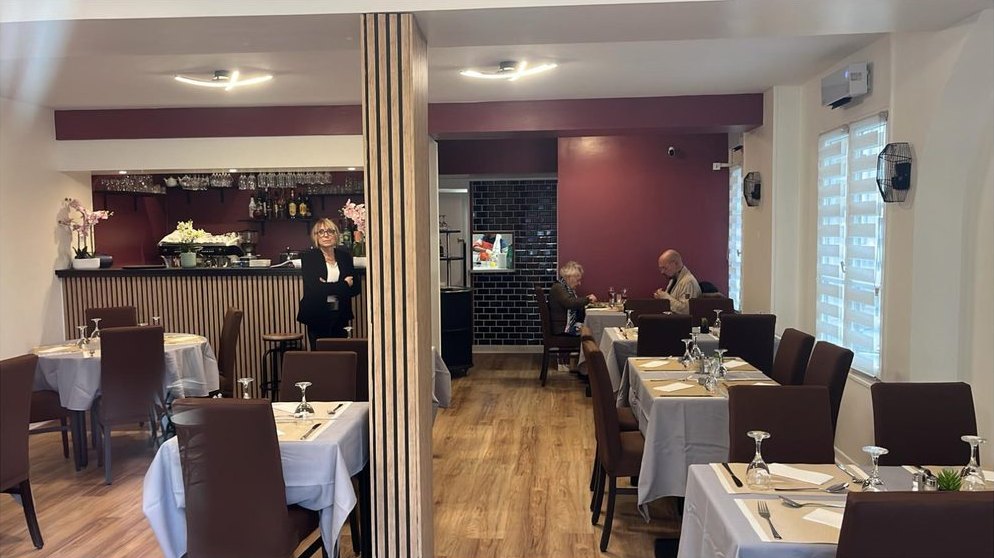 La salle de La Fusion, ses tables dressées, son mur bordeaux et son comptoir en bois